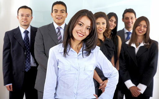 business office team smiling with a woman leading it